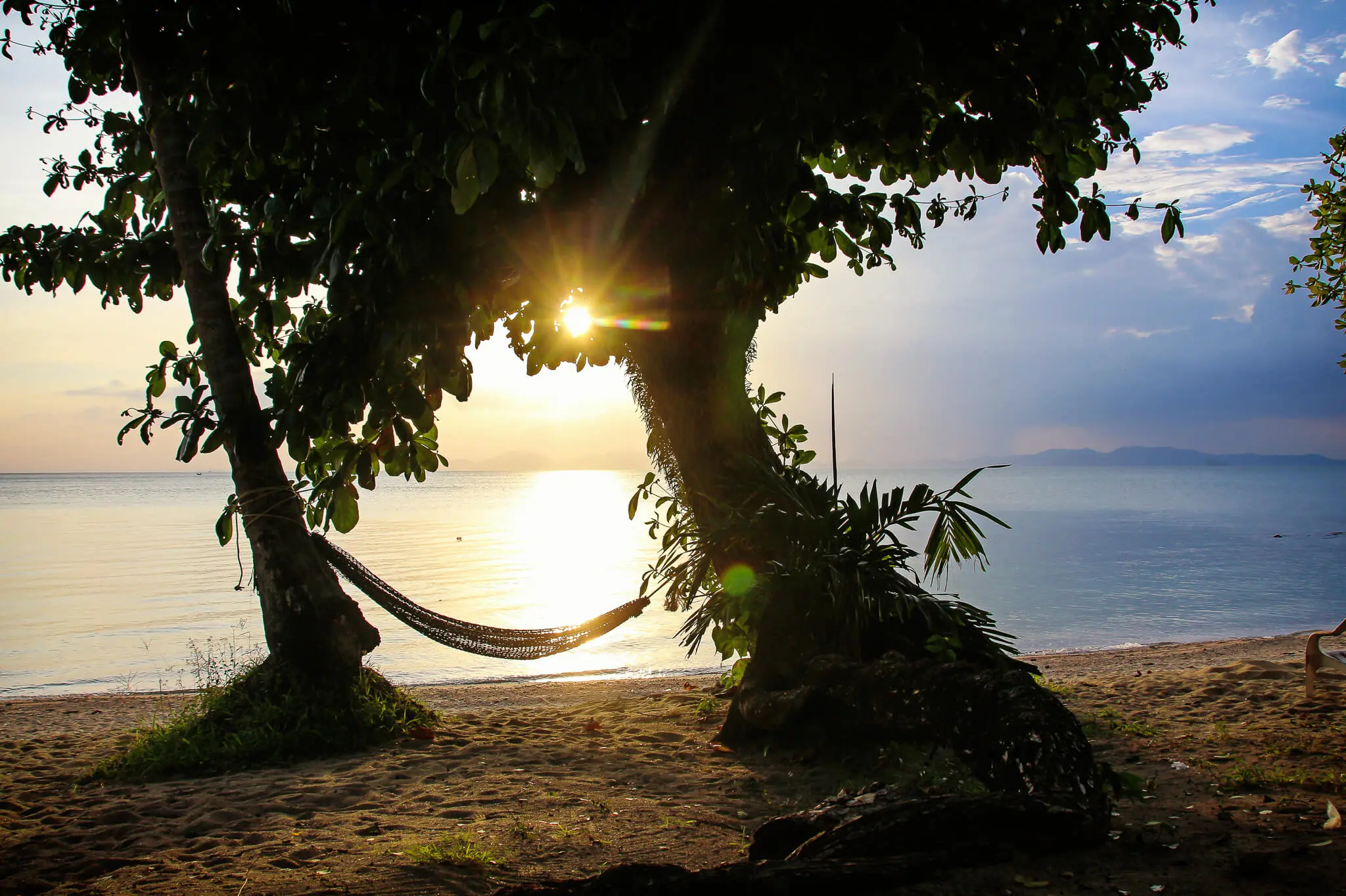 Hängematte zwischen zwei Bäumen am Strand von Thailand bei Sonnenuntergang