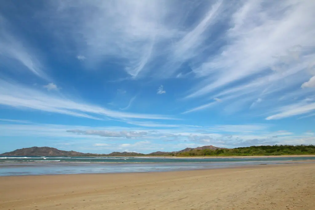 Heller Sandstrand trifft auf ruhige Brandung unter blauem Himmel