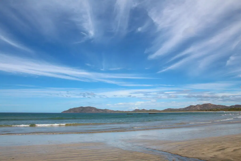 Heller Sandstrand trifft auf ruhige Brandung unter blauem Himmel