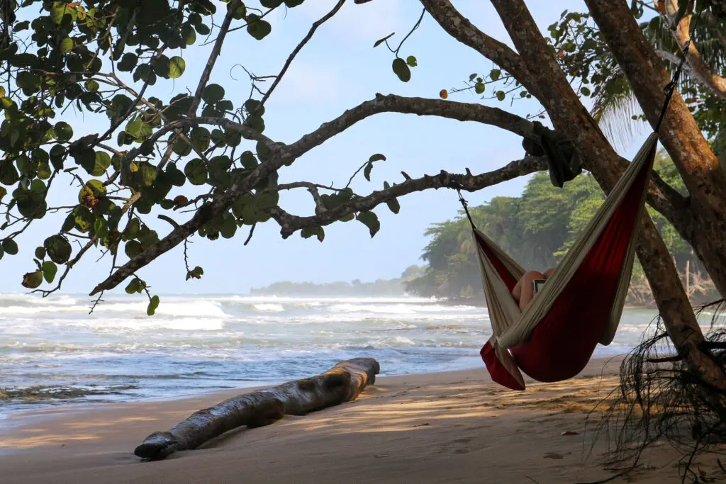 Rote Hängematte zwischen Bäumen mit Blick auf Strand und Meer