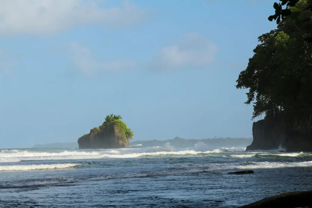 Kleine grüne Felsinsel ragt aus dem Meer vor der Küste