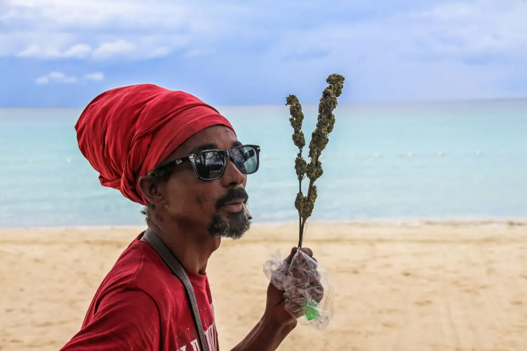 Mann mit rotem Tuch verkauft Kräuter am Strand