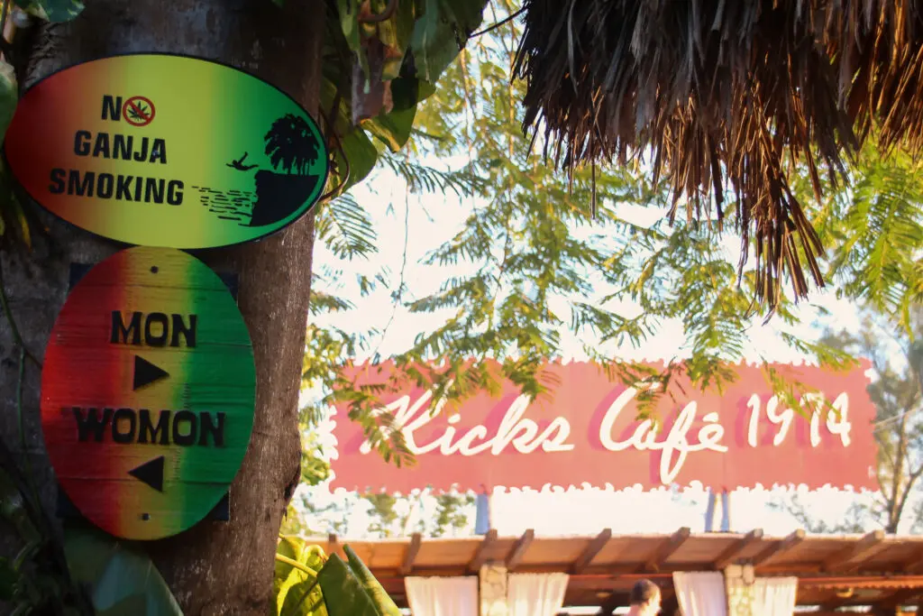 Wegweiser im Grünen mit bunten Schildern zu Bars und Cafés