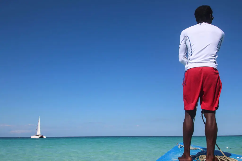 A caribbean dream - travel to Jamaica Mann mit roter Hose steht auf Bootsspitze