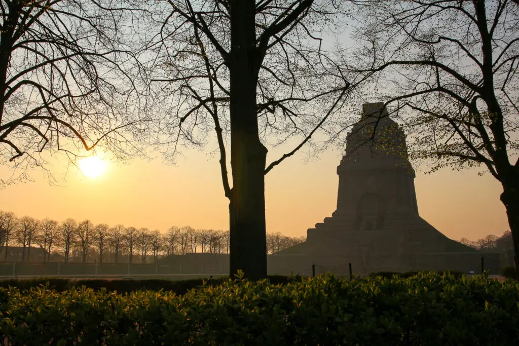 Völkerschlachtdenkmal in Silhouette zwischen Bäumen