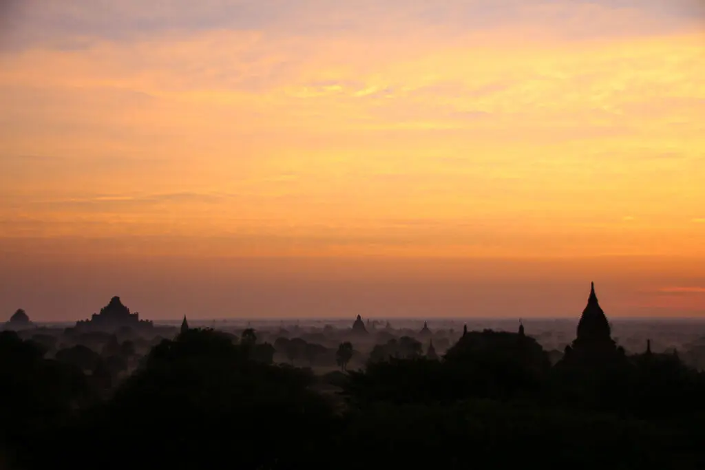 Orangefarbener Sonnenaufgang hinter Silhouetten von Pagoden