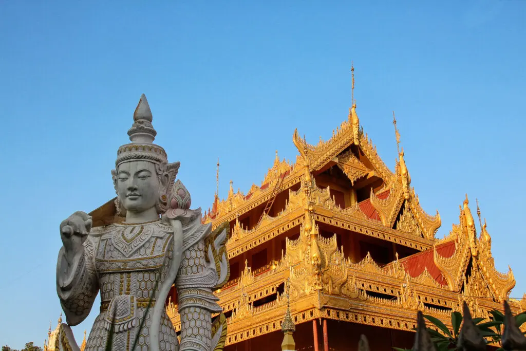 Buddhastatue und Wächterfiguren an einem Tempelportal