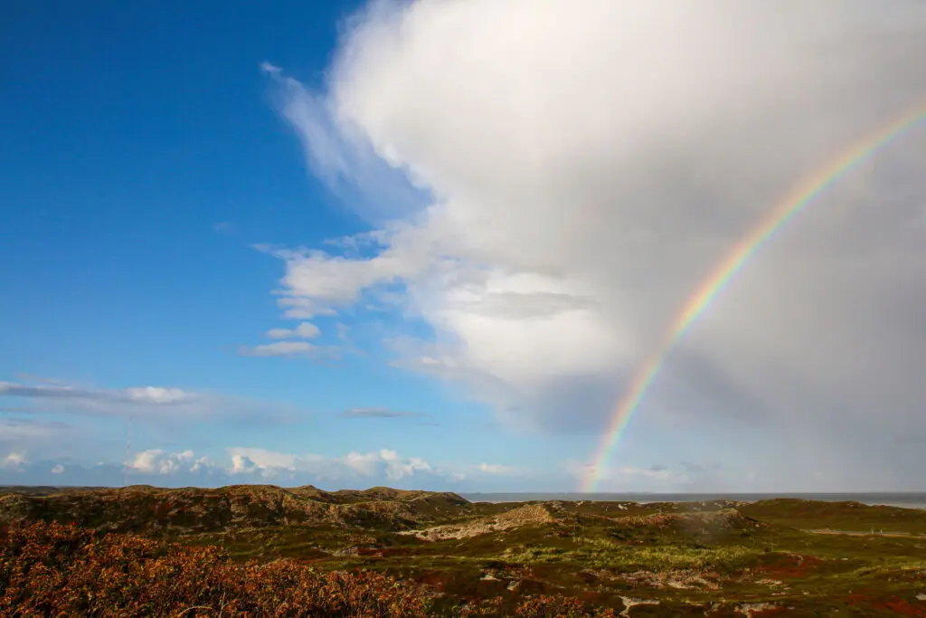Regenbogen unter dramatischem Wolkenhimmel