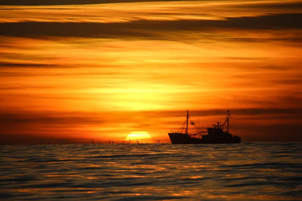Silhouette eines Bootes auf dem Meer bei oranger Abendsonne