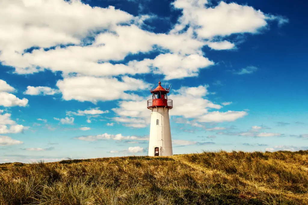 Klassischer Leuchtturm vor tiefblauem Himmel in Dünenlandschaft