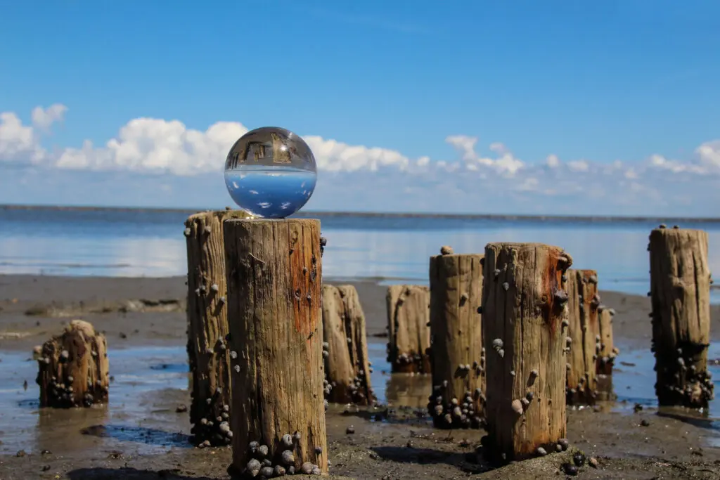 Glaskugel auf Buhnen mit reflektierendem Himmel im Hintergrund