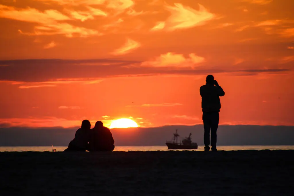 Silhouetten vor einem intensiven Abendhimmel am Strand