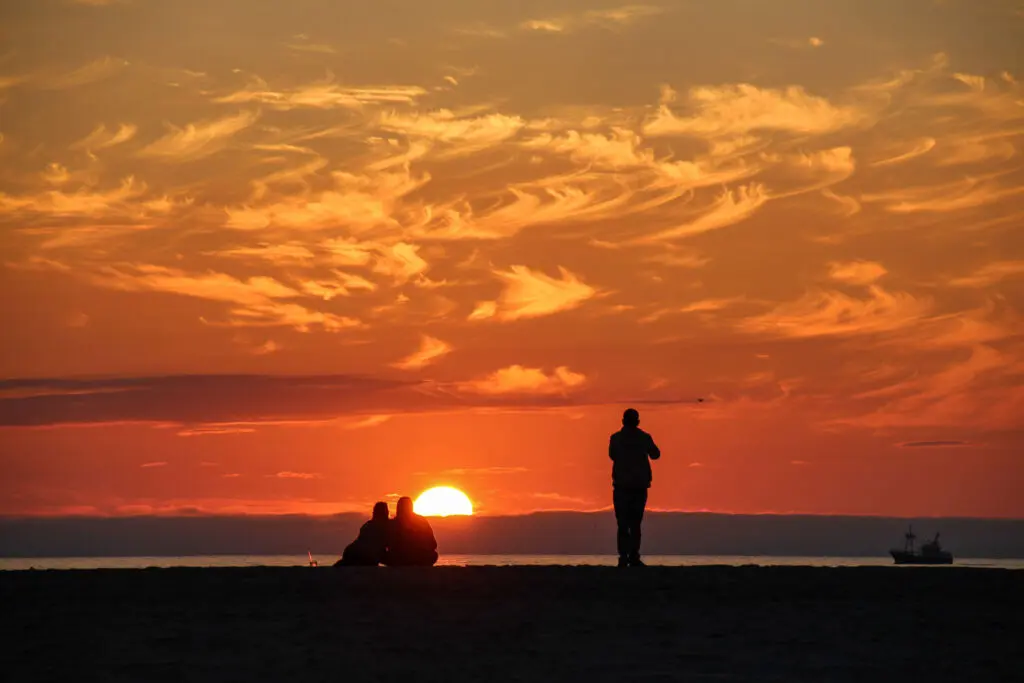 Silhouetten vor einem intensiven Abendhimmel am Strand