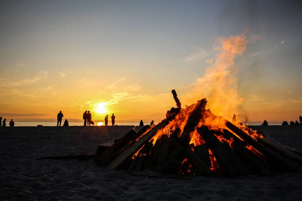 Menschen sitzen am Feuer am Strand in der Dämmerung