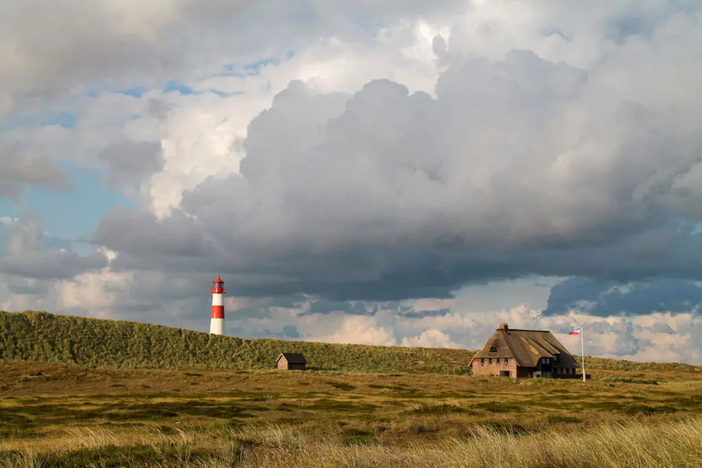 Wolkenverhangener Himmel über sandigen Dünen auf Sylt