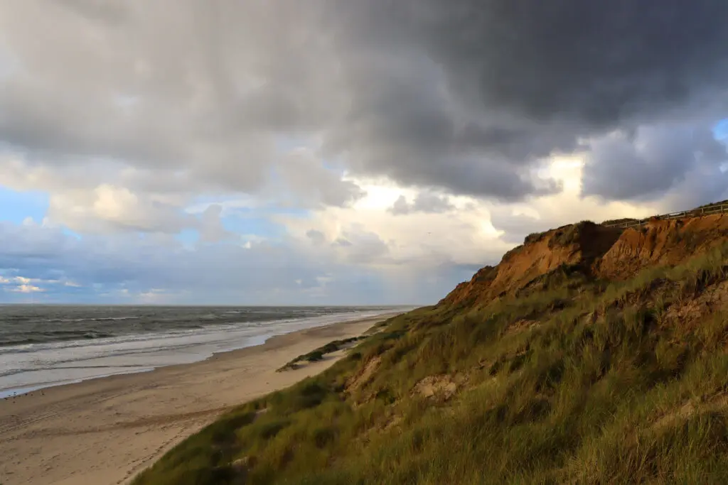 Wolkenverhangener Himmel über sandigen Dünen auf Sylt