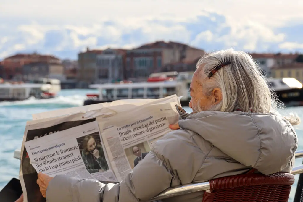 Frau liest Zeitung mit Blick auf die Lagune