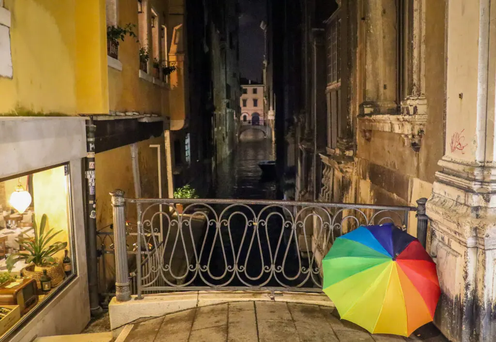 Schmale Gasse mit Brücke und buntem Regenschirm