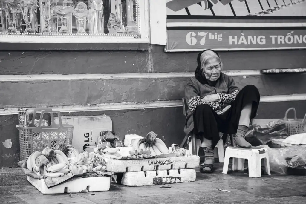 Ältere vietnamesische Frau am Straßenrand mit Waren