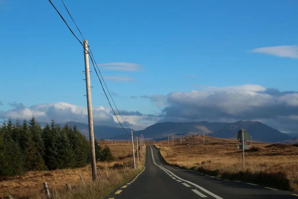 Straße am Nadelwald, Richtung Hügel, Irland