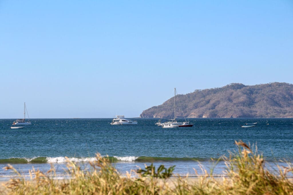 Mehrere Segelboote ankern vor felsiger Bucht im Pazifik