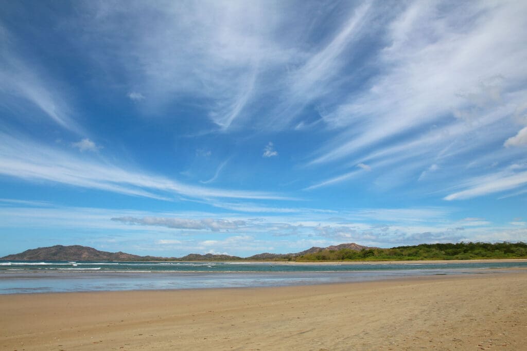 Heller Sandstrand trifft auf ruhige Brandung unter blauem Himmel