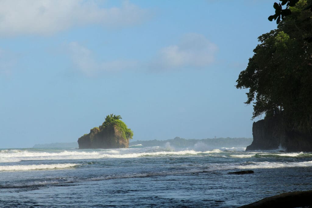 Kleine grüne Felsinsel ragt aus dem Meer vor der Küste