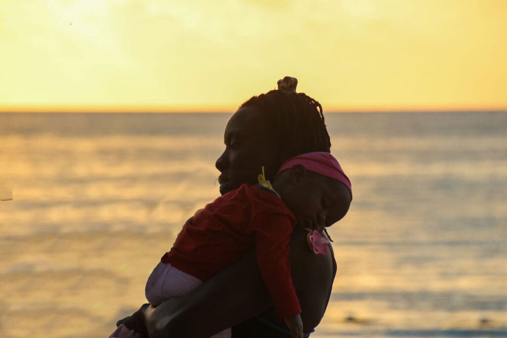 Frau mit Baby bei Sonnenuntergang am Meer