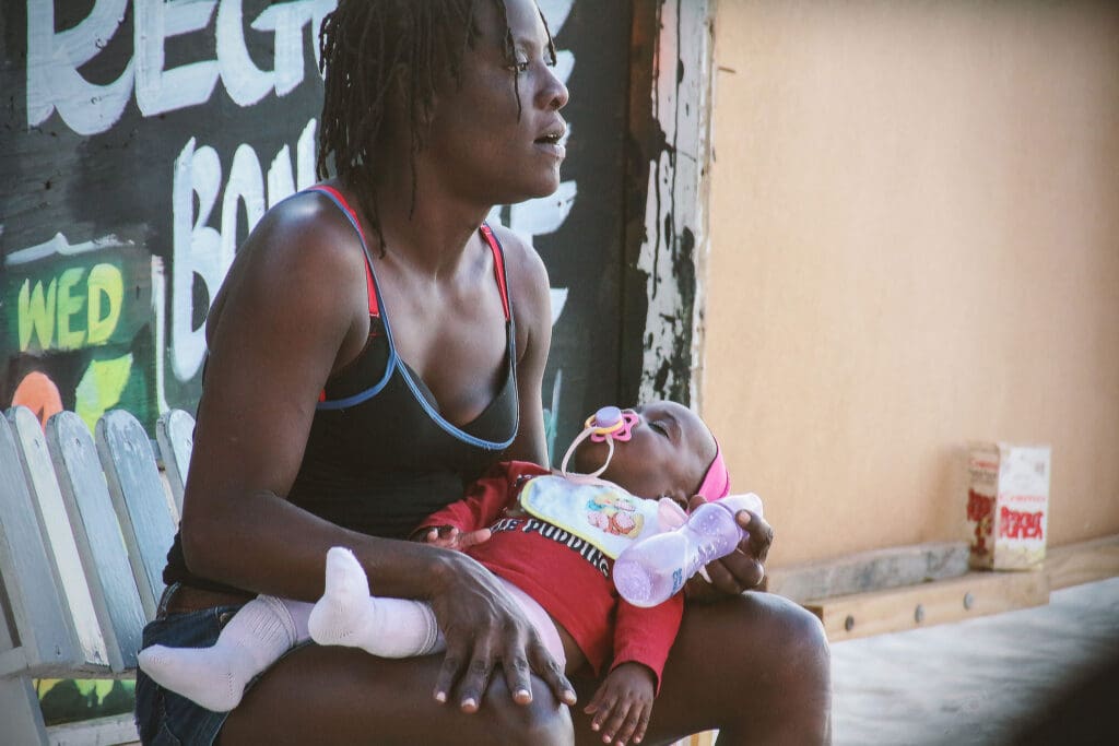 Frau stillt ihr Baby vor Graffiti-Wand in Jamaika