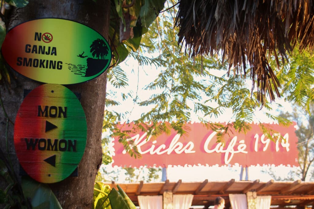 Wegweiser im Grünen mit bunten Schildern zu Bars und Cafés