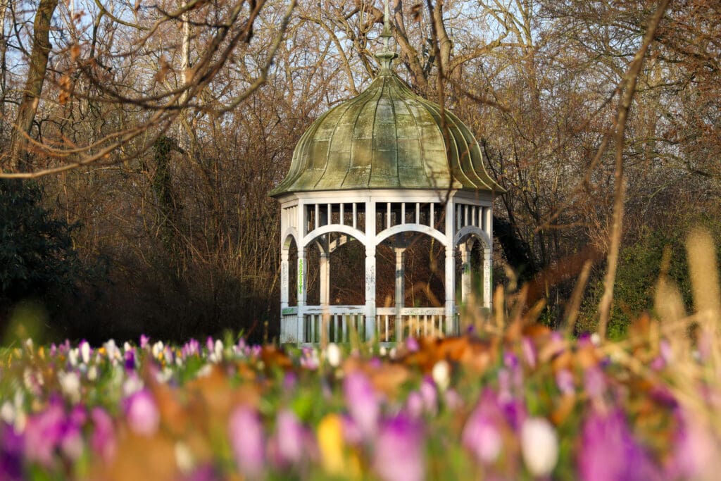 Weißer Pavillon zwischen bunten Frühlingsblumen im Park