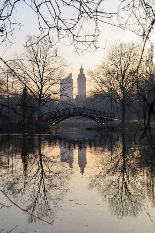 Spiegelung der Leipziger Skyline im Wasser bei Sonnenuntergang