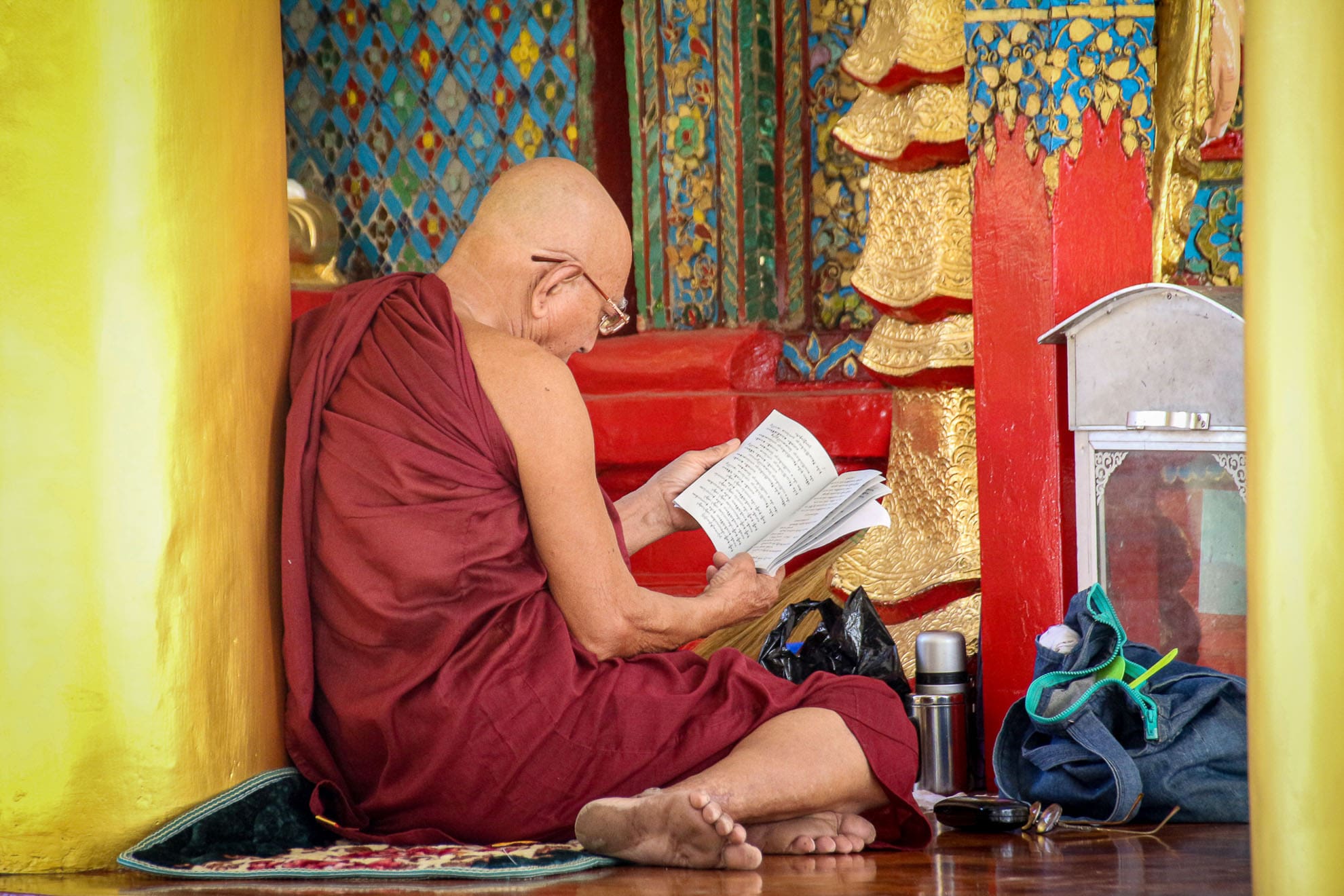 Mönch liest in einem bunt dekorierten Klosterraum