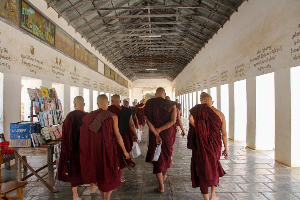 Mönche in roter Robe gehen durch einen Tempelgang