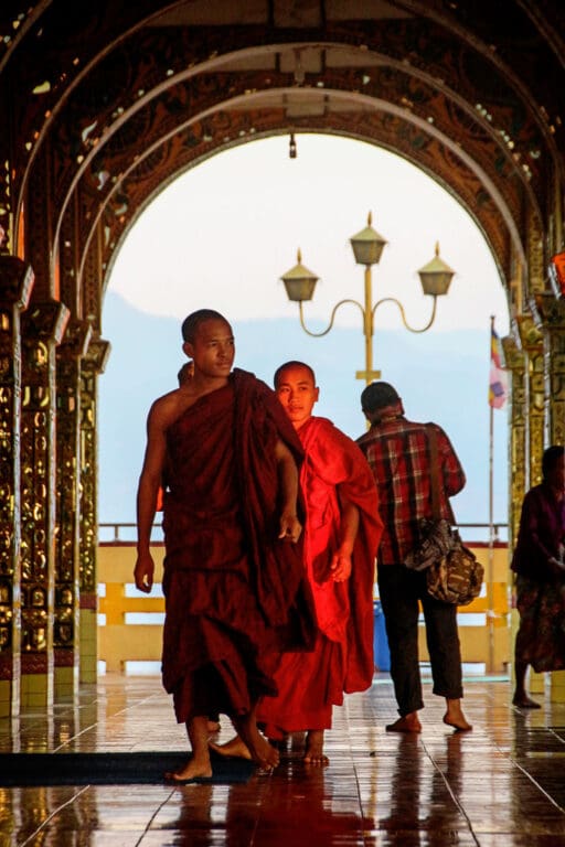 Mönche schreiten durch einen Bogen im Abendlicht