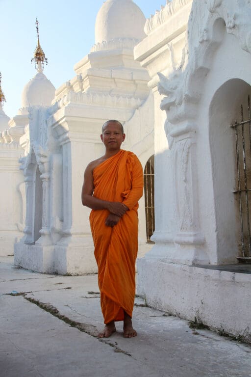 Mönch in Safranrobe spaziert durch weißen Stupahof