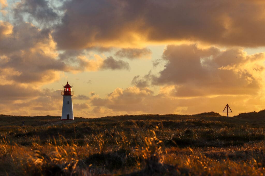 Leuchtturm in Silhouette vor dramatischer Abendsonne
