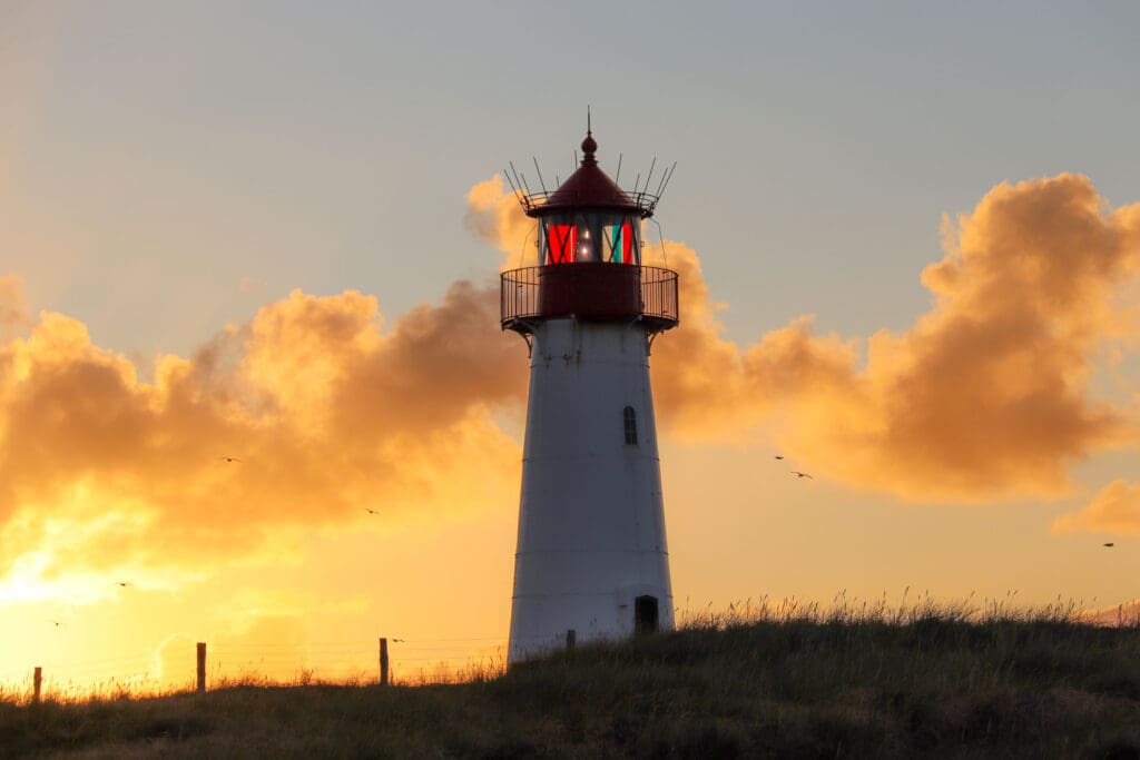 Leuchtturm in Silhouette vor dramatischer Abendsonne