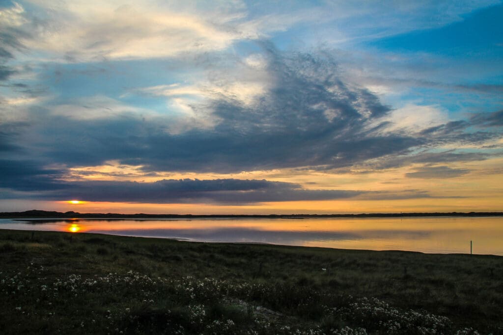 Weite Wolkenformation über dem stillen Wattenmeer bei Sonnenuntergang