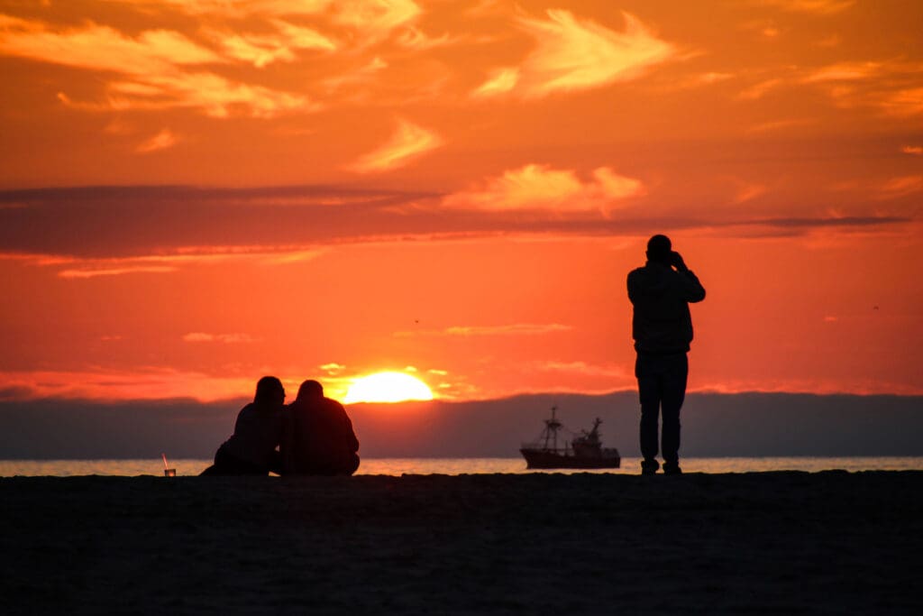 Silhouetten vor einem intensiven Abendhimmel am Strand
