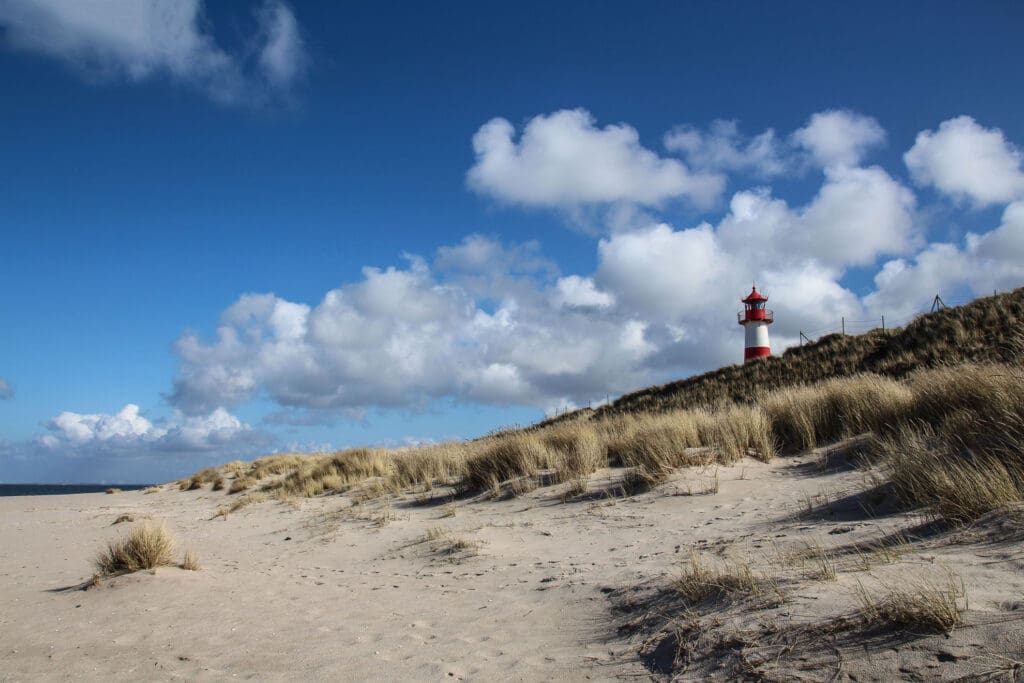 Lister Leuchtturm mit weißen Wolken über den Dünen