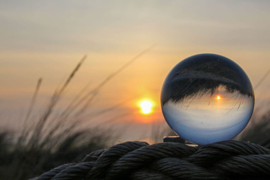 Glaskugel im Gras mit Sonnenuntergang über der Nordsee