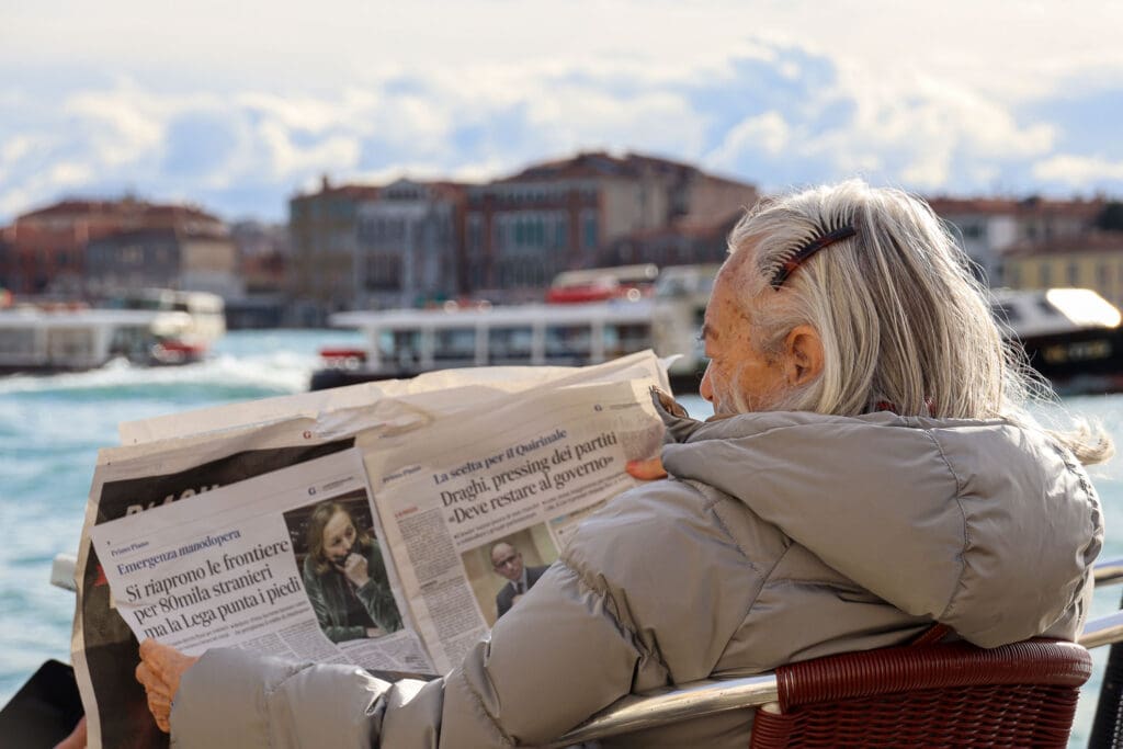 Frau liest Zeitung mit Blick auf die Lagune
