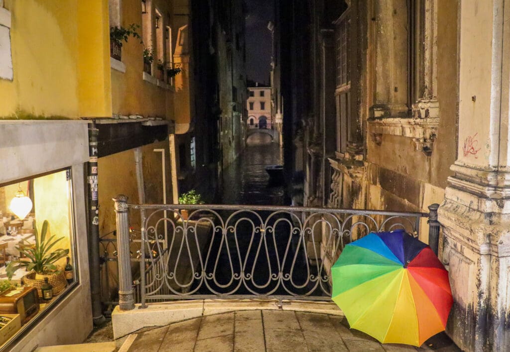 Schmale Gasse mit Brücke und buntem Regenschirm