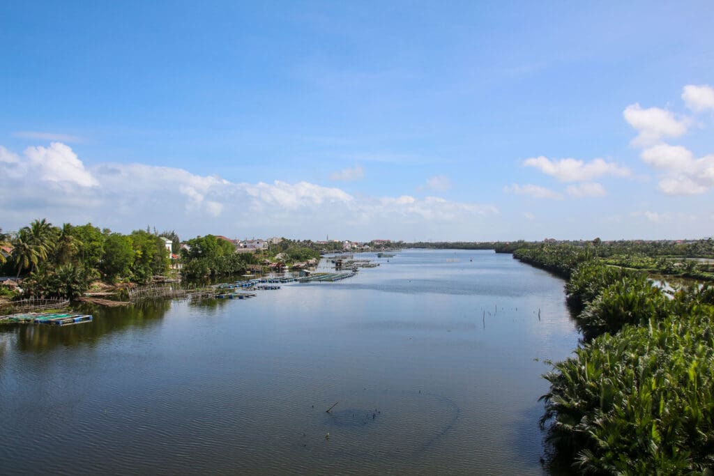 Flusslauf unter Brücke mit grünem Ufer
