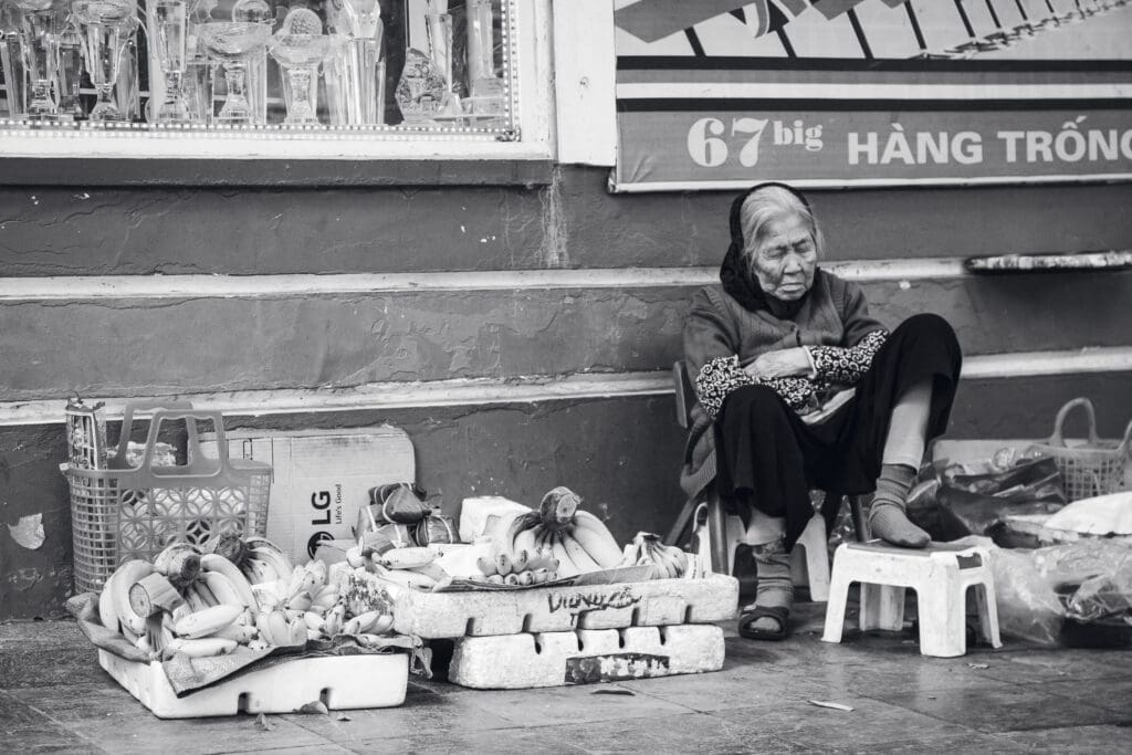 Ältere vietnamesische Frau am Straßenrand mit Waren