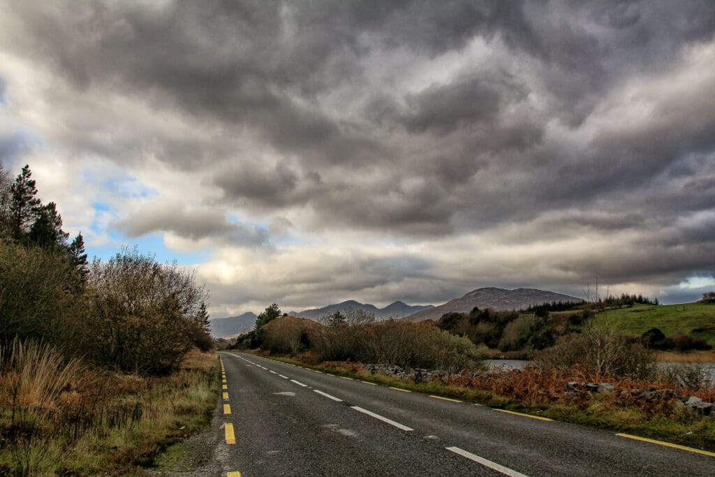 Dunkle Wolken über der Straße, aufziehender Regen, Irland