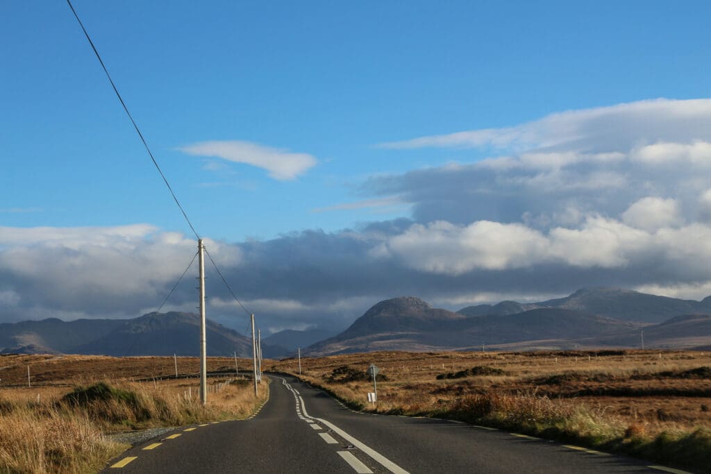 Landstraße durch offene Hügellandschaft, Irland