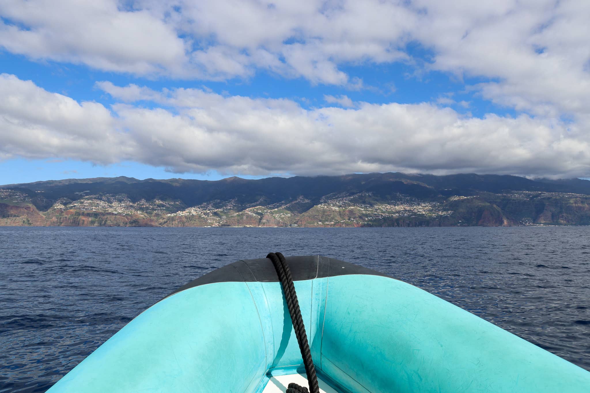 Bootsspitze auf ruhigem Meer mit Felskulisse