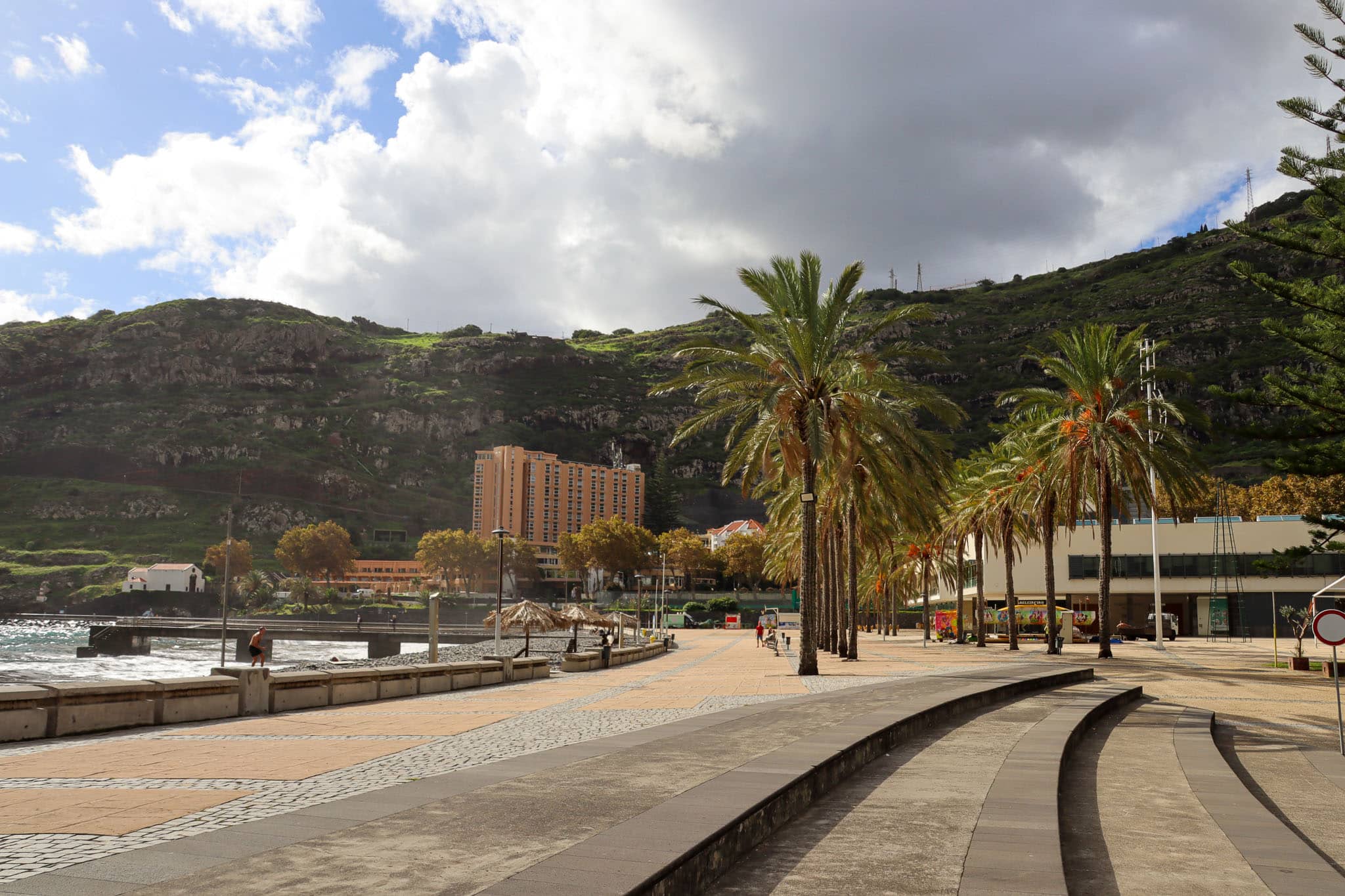 Promenade mit Palmen und Bergen im Hintergrund